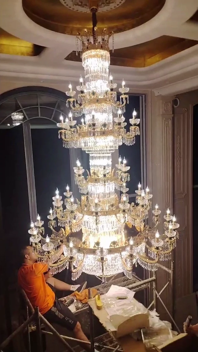 A large chandelier with a person working nearby, shown in the approved film